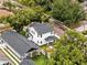 Aerial view of a two-story white home, showcasing its new roof, landscaping, and proximity to mature trees at 502 E Robles St, Tampa, FL 33602