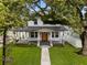 Charming two-story home featuring a spacious front porch framed by mature trees and lush greenery at 502 E Robles St, Tampa, FL 33602