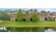 A serene backyard view of the home and pond with lush green lawn and mature trees at 5153 Bay Isle Cir, Clearwater, FL 33760