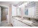 Bright bathroom features double sinks with granite countertops, a cabinet, and walk-in shower at 5319 Lantana St, Zephyrhills, FL 33542