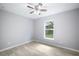 Simple bedroom with light gray walls, a ceiling fan, wood-look tile flooring, and a bright window at 5319 Lantana St, Zephyrhills, FL 33542