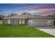 Charming single-story home with a well-manicured lawn, attached garage, and a colorful sunset backdrop at 5319 Lantana St, Zephyrhills, FL 33542
