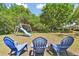 Spacious backyard featuring a wooden playset, three adirondack chairs, and ample green space for recreation at 5813 Bent Grass Dr, Valrico, FL 33596