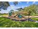 Community playground featuring slides, climbing structures, and swings, all surrounded by green grass and mature trees at 5813 Bent Grass Dr, Valrico, FL 33596
