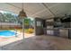 Outdoor kitchen and covered patio next to a pool featuring stainless steel appliances and a mounted TV at 5871 Oakhurst Dr, Seminole, FL 33772