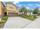 Exterior view of tan townhome with attached garage, landscaped front yard, and palm trees at 6031 Grand Sonata Ave, Lutz, FL 33558