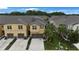 View of townhomes featuring tan exterior, brown garage doors, modern windows, solar panels, and landscaped front yards at 6031 Grand Sonata Ave, Lutz, FL 33558