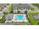 Aerial view of the community pool, lounge area, cabana, lush landscaping, and nearby townhomes at 6031 Grand Sonata Ave, Lutz, FL 33558