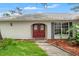 Charming single-story home featuring a well-manicured lawn, mature trees and a red front door at 6058 Waycross Dr, Spring Hill, FL 34606