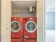 Convenient laundry closet features a modern red washer and dryer set with extra storage space at 7410 E Bank Dr, Tampa, FL 33617
