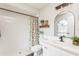 Bright bathroom featuring white tile shower, floral shower curtain, and white vanity with a pink countertop at 8549 Pinafore Dr, New Port Richey, FL 34653