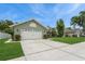 Side view of a single-story home featuring a two-car garage, landscaped lawn, and a glimpse of the backyard at 8549 Pinafore Dr, New Port Richey, FL 34653