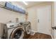 Laundry room featuring front loading washer and dryer, white shelving unit, light colored walls and tile floor at 8549 Pinafore Dr, New Port Richey, FL 34653