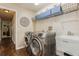 Laundry room featuring front loading washer and dryer, white utility sink, light colored walls, and dark tile floors at 8549 Pinafore Dr, New Port Richey, FL 34653