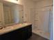 Bathroom with double vanity, framed mirror, and walk-in shower with glass enclosure and tiled surround at 9724 Troncais Cir, Thonotosassa, FL 33592