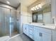Bathroom featuring double sinks, white cabinets, quartz counters, glass shower, and tile flooring at 10347 Heron Hideaway Loop, Land O Lakes, FL 34638