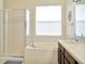 Bright bathroom featuring a soaking tub, glass shower, and single sink at 11123 Silver Dancer Dr, Riverview, FL 33579