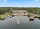 Aerial view of a clubhouse with a pool, deck chairs, a dock, and lake with fountain feature at 11334 Winwood Pl # 11334, Port Richey, FL 34668