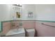 Charming vintage bathroom featuring pink and green tile, a white sink and toilet, and ample storage at 1305 Marion S Dr, St Petersburg, FL 33707