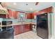 Well-lit kitchen with wood cabinets, black appliances and white tile floor at 1511 East Emma St. E St, Tampa, FL 33610