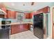 Well-lit kitchen with wood cabinets, black appliances and white tile floors at 1511 East Emma St. E St, Tampa, FL 33610