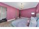 Stylish bedroom showcasing a luxurious chandelier, light wood floors, and ensuite access at 1558 Cottonwood Ter, Dunedin, FL 34698
