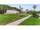 View of a single-story house, green lawn with a sidewalk running adjacent to the property at 1558 Cottonwood Ter, Dunedin, FL 34698