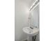 Cozy half bath featuring a pedestal sink, updated fixture, and a framed mirror at 16314 Parkstone Palms Ct, Tampa, FL 33647