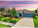 Charming single-story home with a well-maintained lawn, mature trees, and attached two-car garage under a colorful sky at 17136 Sunshine Mimosa: St, Wimauma, FL 33598
