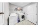 Functional laundry room with washer, dryer, shelving for storage, and a door leading to other areas of the home at 17136 Sunshine Mimosa: St, Wimauma, FL 33598