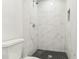 Modern bathroom with a walk-in shower featuring marble-like tile and stylish black hexagonal floor tiling at 1807 E Bougainvillea Ave, Tampa, FL 33612