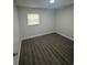 An empty bedroom with gray laminate wood floors and a single window at 1807 E Bougainvillea Ave, Tampa, FL 33612