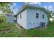 Back exterior featuring light blue paint, lush grass, and large trees at 1807 E Bougainvillea Ave, Tampa, FL 33612