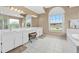 Bathroom with double vanity, large mirrors, a window, and tile flooring at 18219 Bittern Ave, Lutz, FL 33558