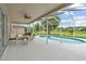 Relaxing outdoor patio with a dining set and a ceiling fan, overlooking a sparkling pool and a tranquil waterfront view at 18219 Bittern Ave, Lutz, FL 33558