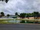 Community pond with fountain feature, lined with lawn and trees at 2015 Vista Del Sol # 108, Lutz, FL 33558