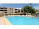 Large community pool with lounge chairs and tropical landscaping at 2616 Cove Cay Dr # 505, Clearwater, FL 33760