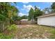 A spacious backyard with a wooden fence, lush greenery, and a detached white garage at 310 N Lincoln Ave, Clearwater, FL 33755