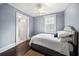 Cozy bedroom with blue walls, hardwood floors, a ceiling fan, and white bedding with easy bathroom access at 310 N Lincoln Ave, Clearwater, FL 33755