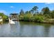 Scenic waterfront view with a boat dock and lift surrounded by lush greenery at 3397 Bluefish Dr, Hernando Beach, FL 34607
