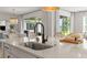 Large kitchen island with a stainless steel sink, seating for four, and pendant lighting overlooking backyard at 3541 Great Banyan Way, Wesley Chapel, FL 33543
