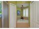 Bathroom featuring garden tub, shower, tiled floors, neutral decor, and shuttered window at 4516 Seagull Dr # 601, New Port Richey, FL 34652