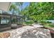 An outdoor oasis featuring a screened-in lanai and a beautiful brick patio surrounded by lush landscaping and mature trees at 5053 18Th St, Zephyrhills, FL 33542
