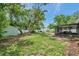 A spacious backyard featuring a screened-in lanai, storage shed, lush greenery, and mature trees at 5053 18Th St, Zephyrhills, FL 33542