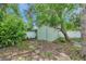 Backyard storage shed with a white privacy fence and surrounded by mature trees and lush greenery at 5053 18Th St, Zephyrhills, FL 33542