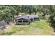 View of home's exterior with metal roof, shaded carport, ladder and ample yard space surrounded by mature trees at 5106 Five Acre Rd, Plant City, FL 33565