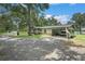 Single-story home with attached carport and circular driveway, nestled amongst mature trees at 5106 Five Acre Rd, Plant City, FL 33565