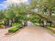 Gated community entrance featuring stone pillars, lush landscaping, and a brick-paved driveway at 512 Creekside Ct, Safety Harbor, FL 34695