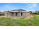 Rear exterior showcasing a covered patio, neutral color palette, and a well-maintained lawn at 5441 Chestnut Ridge Rd, Dade City, FL 33523