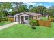 Charming home featuring lush green lawn, cute palm tree, and a partially fenced yard at 6220 Pershing Ne St, St Petersburg, FL 33702